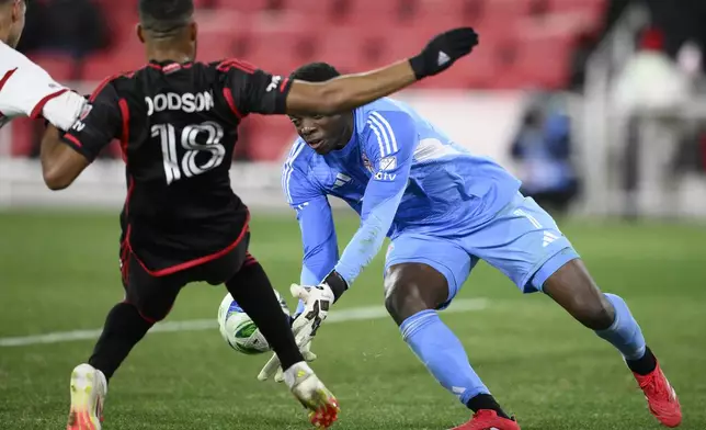 Toronto FC goalkeeper Sean Johnson, right, grabs the ball against D.C. United defender Derek Dodson (18) during the second half of an MLS soccer match, Saturday, Feb. 22, 2025, in Washington. (AP Photo/Nick Wass)