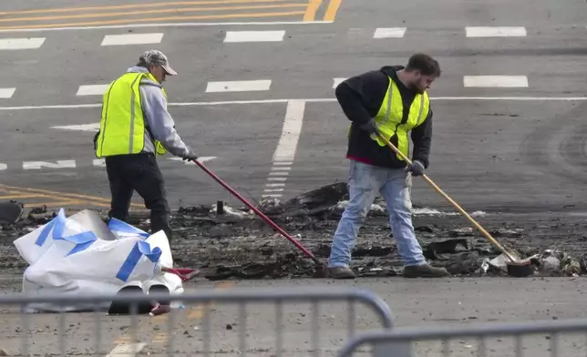 Workers collect debris in the aftermath of a fatal small plane crashed in Philadelphia, Monday, Feb. 3, 2025. (AP Photo/Matt Rourke)