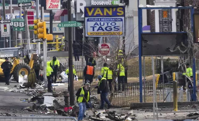 Workers collect debris in the aftermath of a fatal small plane crashed in Philadelphia, Monday, Feb. 3, 2025. (AP Photo/Matt Rourke)