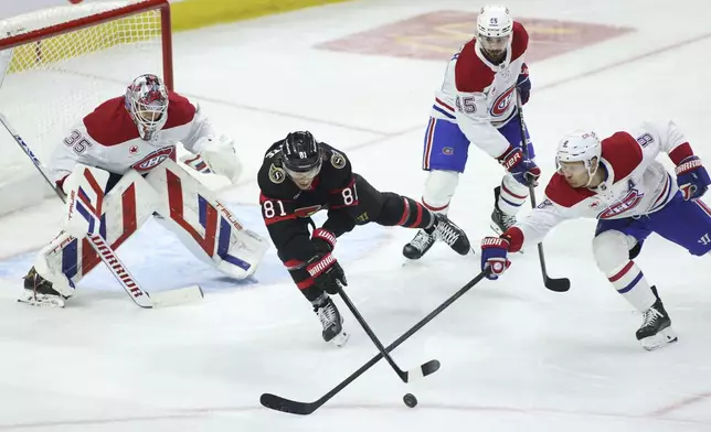 Ottawa Senators' Adam Gaudette (81) and Montreal Canadiens' Mike Matheson (8) reach for the puck as Montreal Canadiens' goaltender Sam Montembeault (35) and Montreal Canadiens' Alexandre Carrier (45) look on during first period NHL hockey action in Ottawa on Saturday, Feb. 22, 2025. (Patrick Doyle/The Canadian Press via AP)