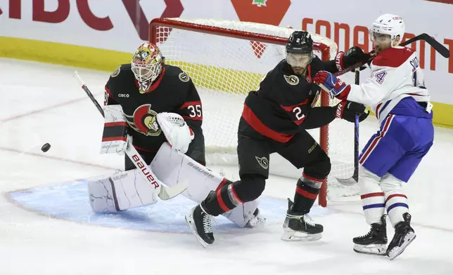 Ottawa Senators' goaltender Linus Ullmark (35) eyes the puck as Ottawa Senators' Artem Zub (2) and Montreal Canadiens' Nick Suzuki (14) jostle during first period NHL hockey action in Ottawa on Saturday, Feb. 22, 2025. (Patrick Doyle/The Canadian Press via AP)