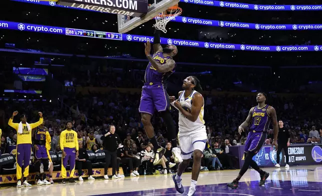 Los Angeles Lakers forward LeBron James scores a basket against Golden State Warriors forward Kevon Looney during the second half of an NBA basketball game Thursday, Feb. 6, 2025, in Los Angeles. (AP Photo/Kevork Djansezian)