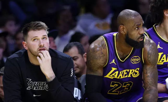 Los Angeles Lakers guard Luka Doncic, left, and forward LeBron James (23) look on from the bench during the first half of an NBA basketball game against the Golden State Warriors, Thursday, Feb. 6, 2025, in Los Angeles. (AP Photo/Kevork Djansezian)