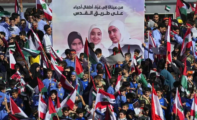 FILE - Students display a poster of the three sisters, Liane, 10; Taline, 12, and Rimas, 14, who were killed with their grandmother, Samira Ayoub, by an Israeli airstrike days earlier, during a protest in front of the headquarters of U.N. Economic and Social Commission for Western Asia (ESCWA) in Beirut, Lebanon, Thursday, Nov. 9, 2023. Arabic words read, "From Ainata to Gaza, living children on the path to Jerusalem" (AP Photo/Bilal Hussein, File)