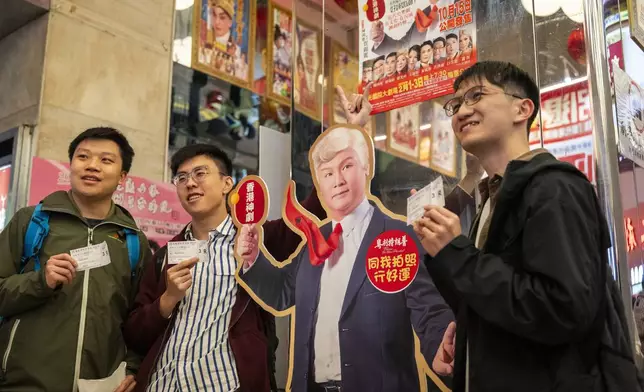 Members of the audience take photographs with a cutout of an actor portraying U.S. President Donald Trump from the Cantonese opera production “Trump on Show” at the Sunbeam Theatre in Hong Kong, Monday, Feb. 3, 2025. (AP Photo/Chan Long Hei)