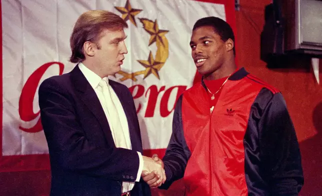 FILE - Donald Trump shakes hands with Herschel Walker in New York after agreement on a 4-year contract with the New Jersey Generals USFL football team, March 8, 1984. (AP Photo/Dave Pickoff, File)