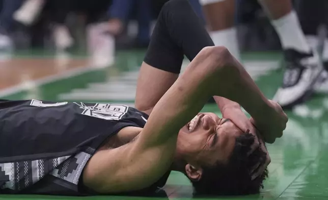 San Antonio Spurs center Victor Wembanyama grabs his head after getting knocked to the floor against the Boston Celtics during the first half of an NBA basketball game, Wednesday, Feb. 12, 2025, in Boston. (AP Photo/Charles Krupa)