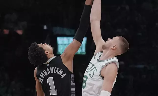 Boston Celtics center Kristaps Porzingis, right, battles for the opening tip against San Antonio Spurs center Victor Wembanyama (1) during the first half of an NBA basketball game, Wednesday, Feb. 12, 2025, in Boston. (AP Photo/Charles Krupa)