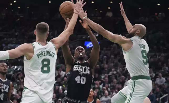 San Antonio Spurs forward Harrison Barnes (40) is covered by Boston Celtics center Kristaps Porzingis (8) and guard Derrick White (9) on a drive to the basket during the first half of an NBA basketball game, Wednesday, Feb. 12, 2025, in Boston. (AP Photo/Charles Krupa)