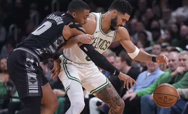 Boston Celtics forward Jayson Tatum, right, tries to hold back San Antonio Spurs forward Keldon Johnson on a steal attempt during the first half of an NBA basketball game, Wednesday, Feb. 12, 2025, in Boston. (AP Photo/Charles Krupa)