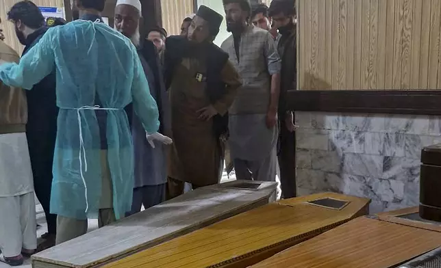 People stand next to the caskets of the victims of bomb explosion in a mosque within a pro-Taliban seminary, at a hospital in Nowshera, a town in the Pakistan's northwestern Khyber Pakhtunkhwa province, Friday, Feb. 28, 2025. (AP Photo/Riaz Khan)