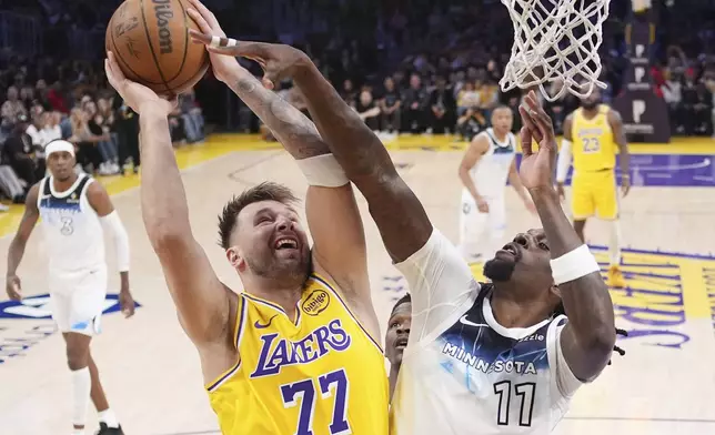 Los Angeles Lakers guard Luka Doncic, left, shoots as Minnesota Timberwolves center Naz Reid defends during the first half of an NBA basketball game, Thursday, Feb. 27, 2025, in Los Angeles. (AP Photo/Mark J. Terrill)