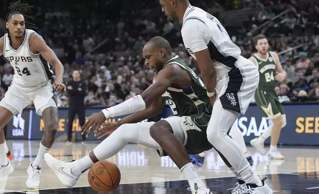 Milwaukee Bucks forward Khris Middleton, center, is fouled by San Antonio Spurs guard Chris Paul, right, during the first half of an NBA basketball game in San Antonio, Friday, Jan. 31, 2025. (AP Photo/Eric Gay)