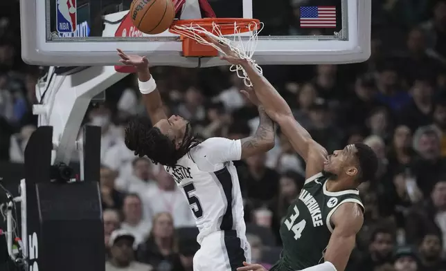 San Antonio Spurs guard Stephon Castle (5) is fouled as he drives to the basket against Milwaukee Bucks forward Giannis Antetokounmpo (34) during the first half of an NBA basketball game in San Antonio, Friday, Jan. 31, 2025. (AP Photo/Eric Gay)