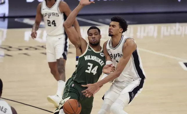 San Antonio Spurs center Victor Wembanyama (1) is defended by Milwaukee Bucks forward Giannis Antetokounmpo (34) during the first half of an NBA basketball game in San Antonio, Friday, Jan. 31, 2025. (AP Photo/Eric Gay)
