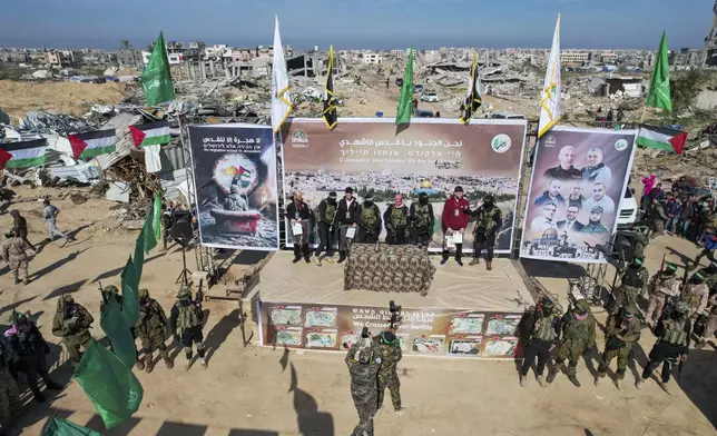 Israeli hostages Iair Horn, 46, left, Sagui Dekel Chen, 36, center left, and Alexander Troufanov, 29, right, are escorted by Hamas and islamic Jihad fighters on a stage before being handed over to the Red Cross in Khan Younis, Gaza Strip, Saturday, Feb. 15, 2025.(AP Photo/Mohammad Abu Samra)