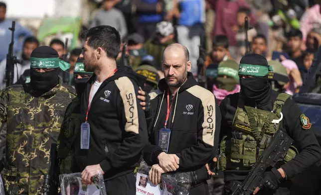 Hostages Iair Horn, 46, Israeli-Argentine, center, and Sagui Dekel Chen, 36, left, Israeli-American are escorted by Hamas and Islamic Jihad fighters before being handed over to the Red Cross in Khan Younis, Gaza Strip, Saturday, Feb. 15, 2025. (AP Photo/Abdel Kareem Hana)