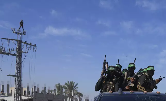Hamas fighters stand on a pick up truck as they arrive for the handover of Israeli captives Iair Horn, Alexander (Sasha) Troufanov, and Sagui Dekel Chen to the Red Cross in Khan Younis, Gaza Strip, Saturday, Feb. 15, 2025. (AP Photo/Abdel Kareem Hana)