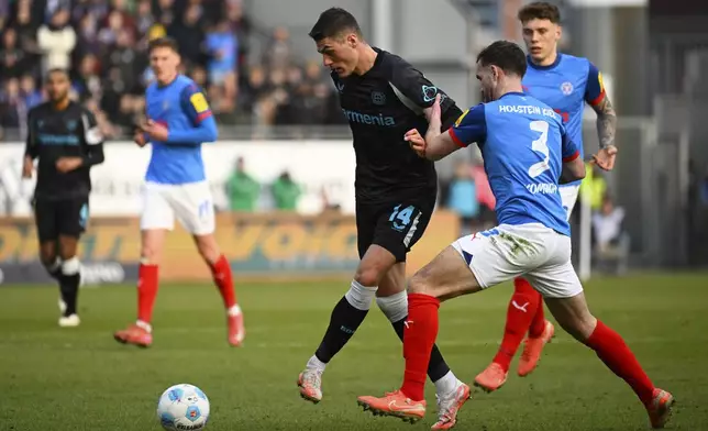 Leverkusen's Patrik Schick and Kiel's Marco Komenda, right, in action during the Bundesliga soccer match between Holstein Kiel and Bayer Leverkusen at Holstein-Stadion, Kiel, Germany, Saturday Feb. 22, 2025. (Gregor Fischer/dpa via AP)
