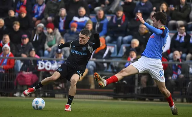 Leverkusen's Florian Wirtz, left, and Kiel's Magnus Knudsen, right, challenge for the ball during the German Bundesliga soccer match between Holstein Kiel and Bayer 04 Leverkusen in Kiel, Germany, Saturday, Feb. 22, 2025. (Gregor Fischer/dpa via AP)