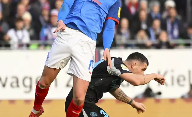 Kiel's Phil Harres, top, and Leverkusen's Granit Xhaka in action during the Bundesliga soccer match between Holstein Kiel and Bayer Leverkusen at Holstein-Stadion, Kiel, Germany, Saturday Feb. 22, 2025. (Gregor Fischer/dpa via AP)