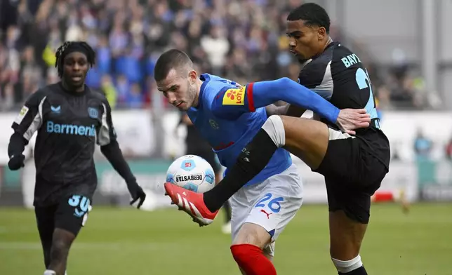 Kiel's David Zac and Leverkusen's Amine Adli, right, in action during the Bundesliga soccer match between Holstein Kiel and Bayer Leverkusen at Holstein-Stadion, Kiel, Germany, Saturday Feb. 22, 2025. (Gregor Fischer/dpa via AP)