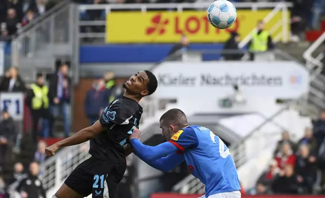 Leverkusen's Amine Adli, left, heads the ball over Kiel's David Zac during the Bundesliga soccer match between Holstein Kiel and Bayer Leverkusen at Holstein-Stadion, Kiel, Germany, Saturday Feb. 22, 2025. (Gregor Fischer/dpa via AP)