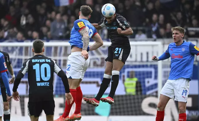 Kiel's Nicolai Remberg, left, and Leverkusen's Amine Adli battle for the ball during the Bundesliga soccer match between Holstein Kiel and Bayer Leverkusen at Holstein-Stadion, Kiel, Germany, Saturday Feb. 22, 2025. (Gregor Fischer/dpa via AP)