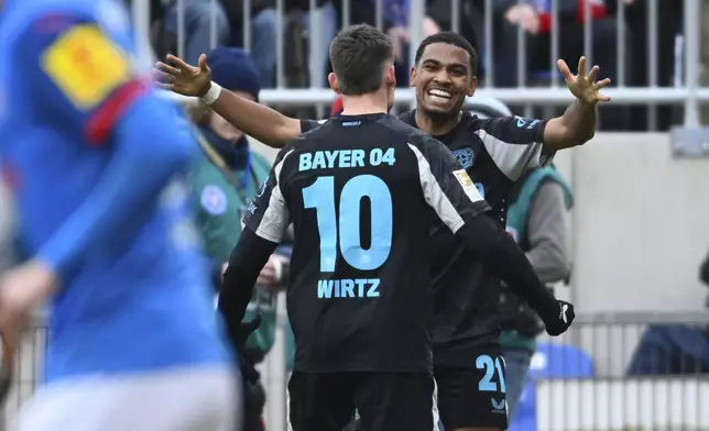 Leverkusen's Amine Adli, right, celebrates scoring with teammate Florian Wirtz during the Bundesliga soccer match between Holstein Kiel and Bayer Leverkusen at Holstein-Stadion, Kiel, Germany, Saturday Feb. 22, 2025. (Gregor Fischer/dpa via AP)