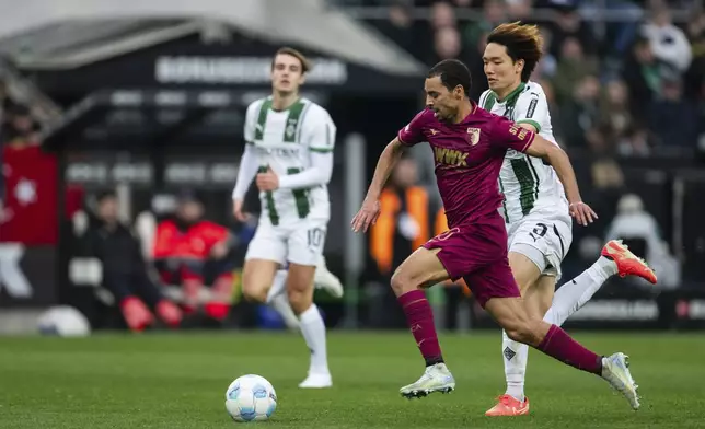 Augsburg's Alexis Claude-Maurice, left, and Gladbach's Ko Itakura fight for the ball during the German Bundesliga soccer match between Borussia Moenchengladbach and FC Augsburg in Moenchengladbach, Germany, Saturday, Feb. 22, 2025. (Marius Becker/dpa via AP)