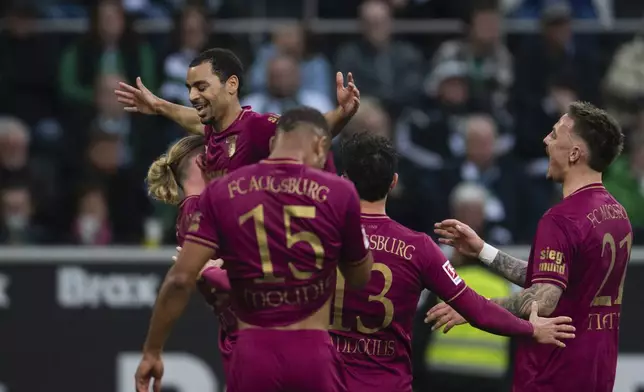 Augsburg's Alexis Claude-Maurice, top, celebrates with teammates after scoring his second goal of the match during the German Bundesliga soccer match between Borussia Moenchengladbach and FC Augsburg in Moenchengladbach, Germany, Saturday, Feb. 22, 2025. (Marius Becker/dpa via AP)