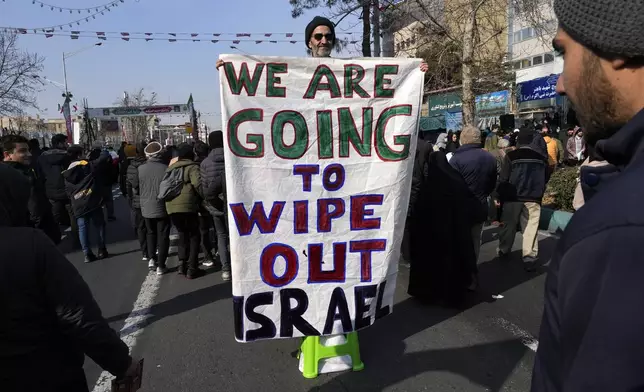 An Iranian demonstrator holds an anti-Israeli banner during a rally commemorating anniversary of 1979 Islamic Revolution that toppled the late pro-U.S. Shah Mohammad Reza Pahlavi and brought Islamic clerics to power, in Tehran, Iran, Monday, Feb. 10, 2025. (AP Photo/Vahid Salemi)