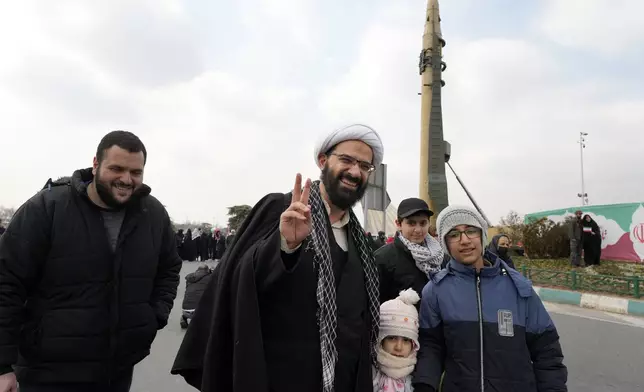 A cleric flashes a victory sign near a domestically-built missile during a rally commemorating anniversary of Iran's 1979 Islamic Revolution that toppled the late pro-U.S. Shah Mohammad Reza Pahlavi and brought Islamic clerics to power, in Tehran, Iran, Monday, Feb. 10, 2025. (AP Photo/Vahid Salemi)