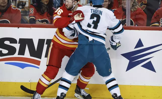 San Jose Sharks' Henry Thrun, right, checks Calgary Flames' Joel Farabee, left, during second-period NHL hockey game action in Calgary, Alberta, Sunday, Feb. 23, 2025. (Jeff McIntosh/The Canadian Press via AP)