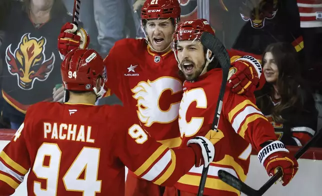Calgary Flames' Kevin Rooney, center, celebrates after his goal with teammates Brayden Pachal, left, and Ryan Lomberg, right, during second-period NHL hockey game action against the San Jose Sharks in Calgary, Alberta, Sunday, Feb. 23, 2025. (Jeff McIntosh/The Canadian Press via AP)