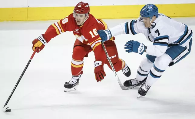 San Jose Sharks' Nico Sturm, right, checks Calgary Flames' Morgan Frost, left, during second-period NHL hockey game action in Calgary, Alberta, Sunday, Feb. 23, 2025. (Jeff McIntosh/The Canadian Press via AP)