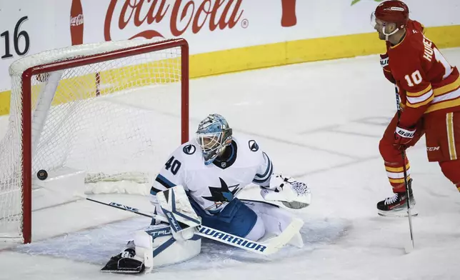 San Jose Sharks goalie Alexandar Georgiev, left, lets in a goal as Calgary Flames' Jonathan Huberdeau, right, looks on during first-period NHL hockey game action in Calgary, Alberta, Sunday, Feb. 23, 2025. (Jeff McIntosh/The Canadian Press via AP)