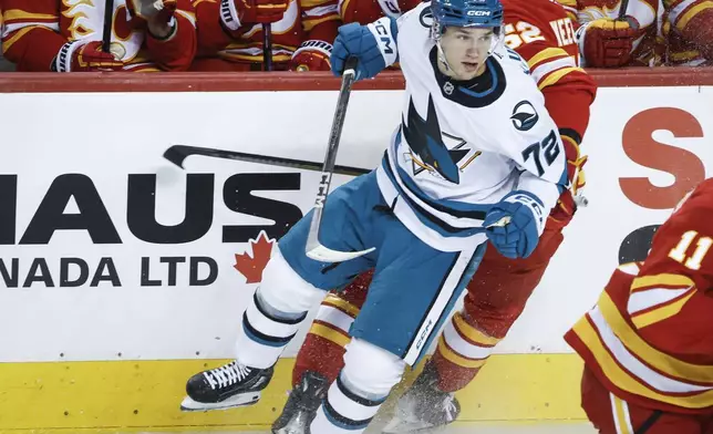 San Jose Sharks' William Eklund (72) checks Calgary Flames' MacKenzie Weegar (52) during first-period NHL hockey game action in Calgary, Alberta, Sunday, Feb. 23, 2025. (Jeff McIntosh/The Canadian Press via AP)