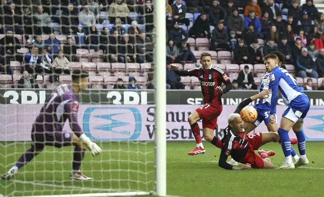 Wigan Athletic's Luke Robinson, right, scores an own goal during the Englsih FA Cup fourth round soccer match between Wigan Athletic and Fulham at The Brick Community Stadium, Wigan, England, Saturday Feb. 8, 2025. (Barrington Coombs/PA via AP)
