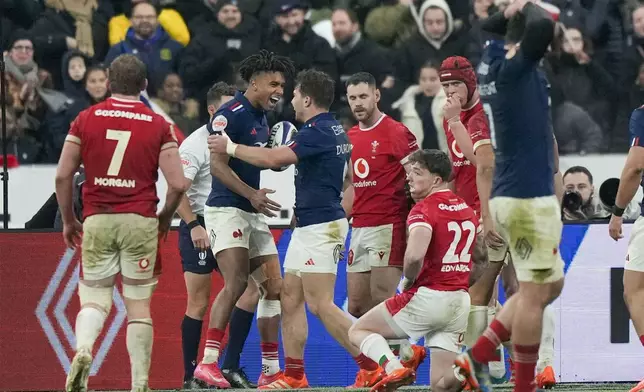 France's Theo Attissogbe, second left, celebrates with Antoine Dupont after scoring a try during the Six Nations rugby union match between France and Wales at the Stade de France in Saint-Denis, outside Paris, Friday, Jan. 31, 2025. (AP Photo/Michel Euler)