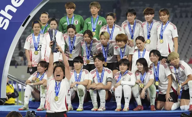 Japan defender Hana Takahashi, below left, raises the trophy as teammates pretend not to notice during celebrations after defeating the United States to win the SheBelieves Cup women's soccer tournament Wednesday, Feb. 26, 2025, in San Diego. (AP Photo/Gregory Bull)