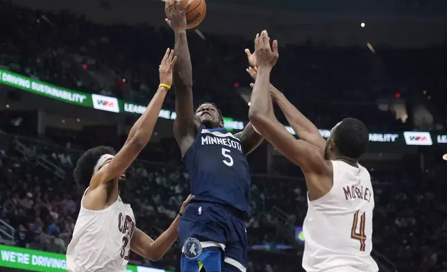 Minnesota Timberwolves guard Anthony Edwards (5) shoots between Cleveland Cavaliers center Jarrett Allen (31) and forward Evan Mobley (4) in the first half of an NBA basketball game Monday, Feb. 10, 2025, in Cleveland. (AP Photo/Sue Ogrocki)