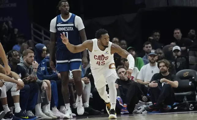 Cleveland Cavaliers guard Donovan Mitchell (45) gestures in front of Minnesota Timberwolves center Naz Reid (11) after hitting a 3-point basket in the first half of an NBA basketball game Monday, Feb. 10, 2025, in Cleveland. (AP Photo/Sue Ogrocki)