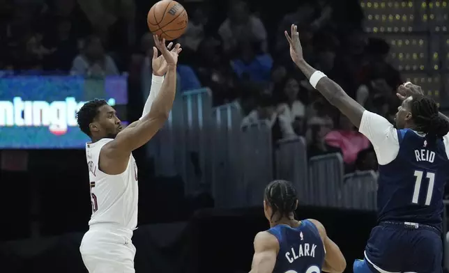 Cleveland Cavaliers guard Donovan Mitchell, left, shoots over Minnesota Timberwolves guard Jaylen Clark, center, and center Naz Reid (11) in the first half of an NBA basketball game Monday, Feb. 10, 2025, in Cleveland. (AP Photo/Sue Ogrocki)