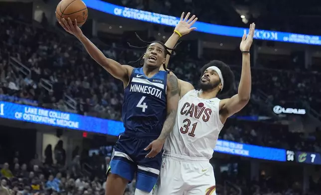Minnesota Timberwolves guard Rob Dillingham (4) goes to the basket in front of Cleveland Cavaliers center Jarrett Allen (31) in the first half of an NBA basketball game Monday, Feb. 10, 2025, in Cleveland. (AP Photo/Sue Ogrocki)
