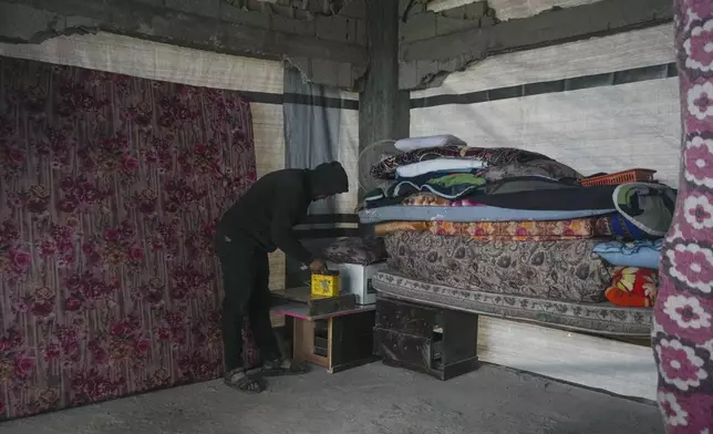 Yousef Odeh, 27, connects a wire to a battery to light up his house in the Jabaliya refugee camp in the northern Gaza Strip, Friday, Feb. 7, 2025. (AP Photo/Abdel Kareem Hana)