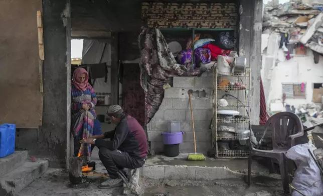 Mariam Odeh speaks with her husband, Ahmed Odeh, sitting next to a small fire to warm himself in the Jabaliya refugee camp in the northern Gaza Strip, Friday, Feb. 7, 2025. (AP Photo/Abdel Kareem Hana)