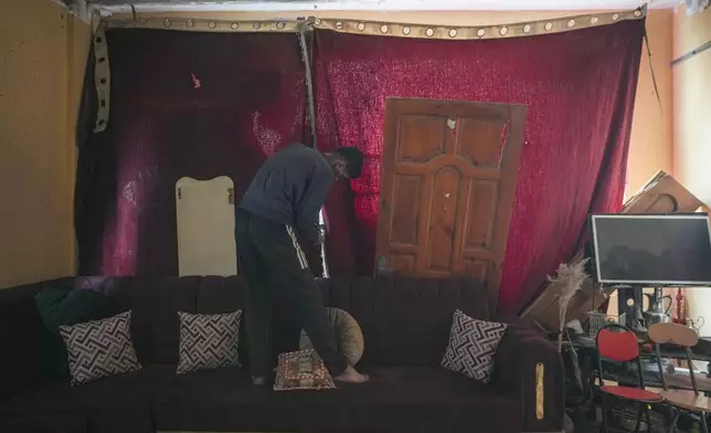 Youssef Issa, 21, uses fabric to cover a hole in a destroyed wall in the Jabaliya refugee camp in the northern Gaza Strip, Friday, Feb. 7, 2025. (AP Photo/Abdel Kareem Hana)