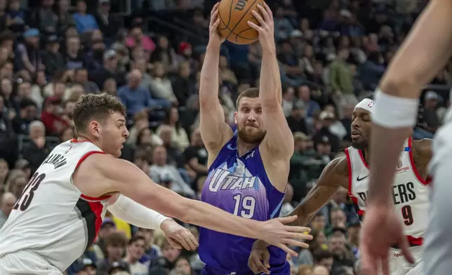 Utah Jazz guard Svi Mykhailiuk (19) makes a move to the basket as Portland Trail Blazers center Donovan Clingan, left, and Jerami Grant (9) defend during the first half of an NBA basketball game Monday, Feb. 24, 2025, in Salt Lake City. (AP Photo/Rick Egan)