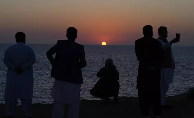 People take pictures as the sun sets along the beach in the coastal city of Gwadar, in the southwest Pakistani province of Balochistan, Jan. 14, 2025. (AP Photo/Anjum Naveed)